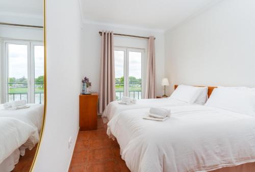 a white bedroom with two beds and a mirror at Hotel Salatia in Alcácer do Sal