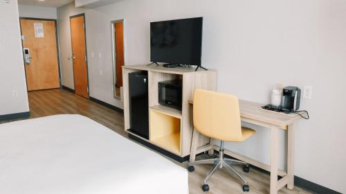a room with a desk with a television and a chair at Microtel Inn & Suites by Wyndham Gulf Shores in Gulf Shores