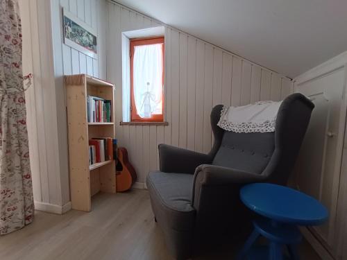 a living room with a chair and a book shelf at Mansarda Eiretta in Ceres