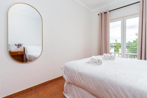 a bedroom with a bed with a mirror and a window at Hotel Salatia in Alcácer do Sal