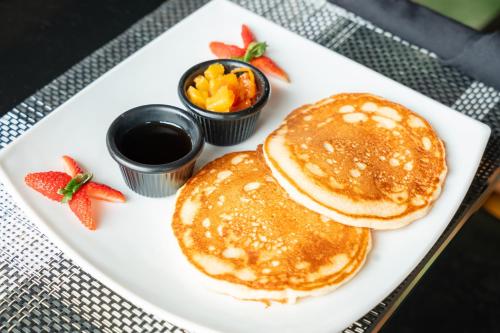 two pancakes on a plate with fruit and syrup at Lake Arenal Hotel & Brewery in Tilarán