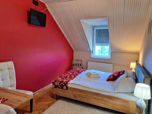 a bedroom with a bed and a red wall at Parrag Panzió Mátraszentimre in Mátraszentimre