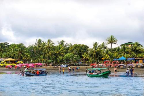 personas en una playa con barcos en el agua en Hotel y cabañas dyd, en Bazán