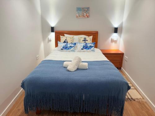 a bedroom with a blue bed with two towels on it at O Marinheiro 15B in Machico