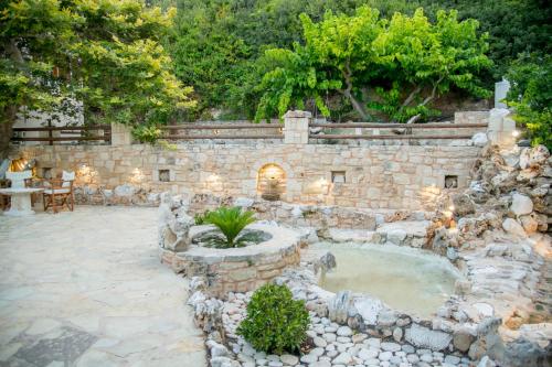 a stone building with a fountain in a yard at Platani Seaside Villa in Sitia