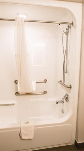 a bathroom with a bath tub with a shower curtain at Microtel Inn & Suites by Wyndham Gulf Shores in Gulf Shores