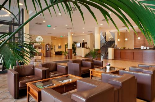 a lobby with chairs and tables in a building at IntercityHotel Bremen in Bremen