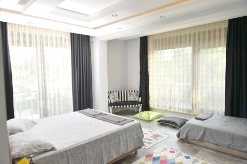 a bedroom with two beds and large windows at Villa Opera Kemer Müstakil Villa in Kemer