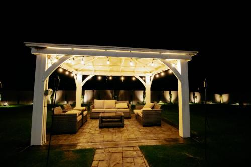 a white pergola with couches on a patio at night at Beautiful Estate in 19 acres of land in Apex in Apex