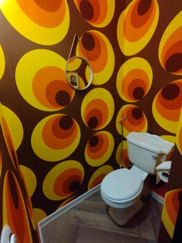 a bathroom with a toilet and a colorful wall at Le Making Of Chambres d'Hôtes insolites et Familiales in Thairé