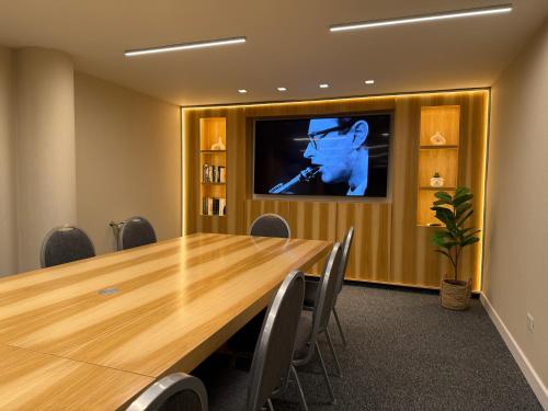 a conference room with a large wooden table and a tv at Hotel Denver Mar del Plata in Mar del Plata