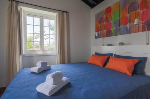 Un dormitorio con una cama azul con dos sombreros. en Oceanfront Casa do Mirante, en Ponta Delgada