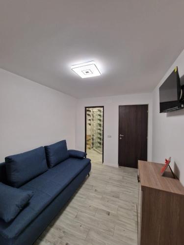 a living room with a blue couch and a television at Apartament LUKE in Tîrgu Ocna
