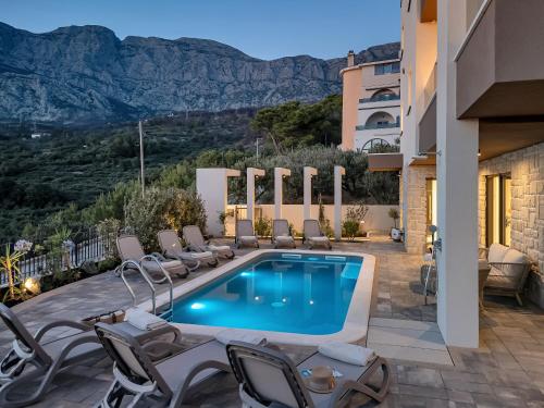 a villa with a swimming pool and chairs at Blue Dream - La Luna Residence in Tučepi