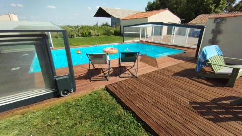a deck with a swimming pool and two chairs at Le Making Of Chambres d'Hôtes insolites et Familiales in Thairé