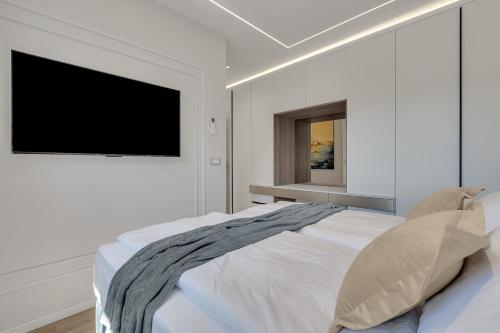 a white bedroom with a bed and a flat screen tv at Blue Dream - La Luna Residence in Tučepi