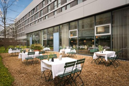 a group of tables and chairs in front of a building at The Rilano Hotel München in Munich