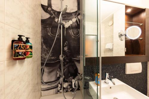a bathroom with a shower with a man in a costume at The Rilano Hotel München in Munich