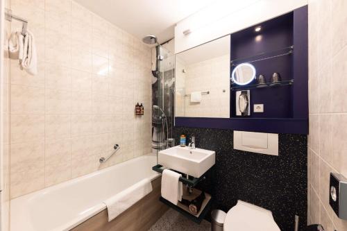 a bathroom with a sink and a toilet and a tub at The Rilano Hotel München in Munich
