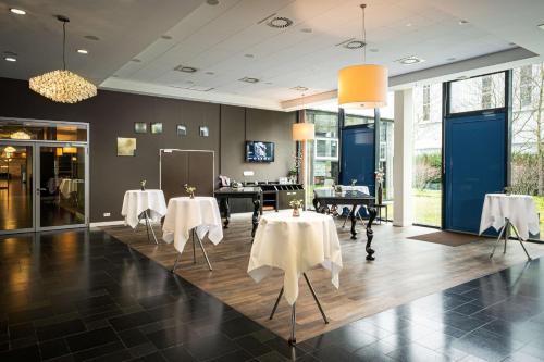 a dining room with two tables with white tablecloths at The Rilano Hotel München in Munich