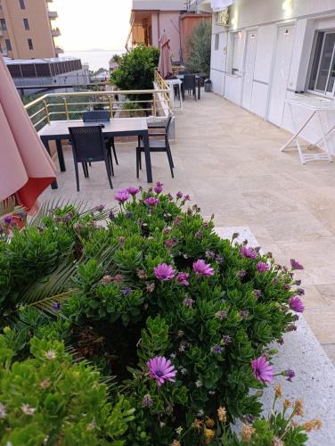 a patio with a table and chairs and flowers at SOLE INN in Vlorë