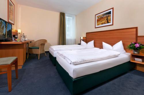 a hotel room with two beds and a desk at IntercityHotel Bremen in Bremen