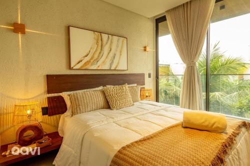 ein Schlafzimmer mit einem großen Bett mit einem großen Fenster in der Unterkunft Casa em condomínio beira mar Serena E1 by Qavi in Barra do Camaragibe