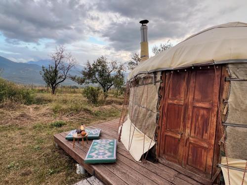 a yurt with a wooden deck with a table in front at Family Eco Farm Getaway in Ryskulovo