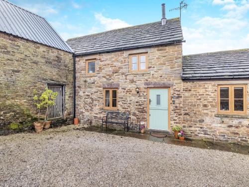 a stone house with a white door and a gravel driveway at The Pig Sty in Barlow