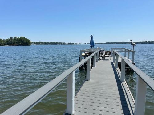 a dock with chairs and an umbrella on the water at Driftwood Dreams in Chapin