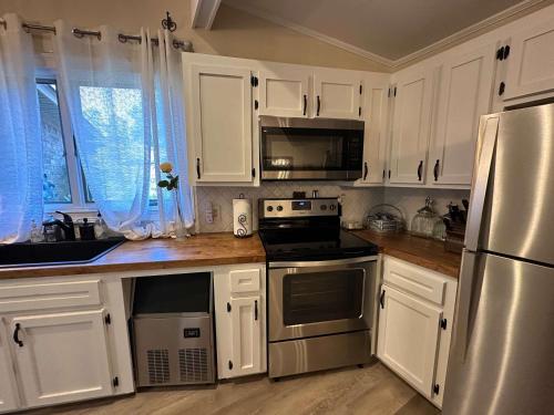 a kitchen with white cabinets and a stainless steel refrigerator at Driftwood Dreams in Chapin