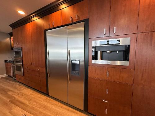 a stainless steel refrigerator in a kitchen with wooden cabinets at Driftwood Dreams in Chapin