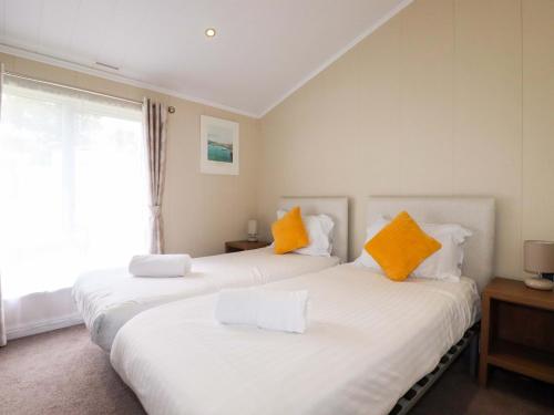 two beds with orange and white pillows in a room at The Maples 44 in St Austell