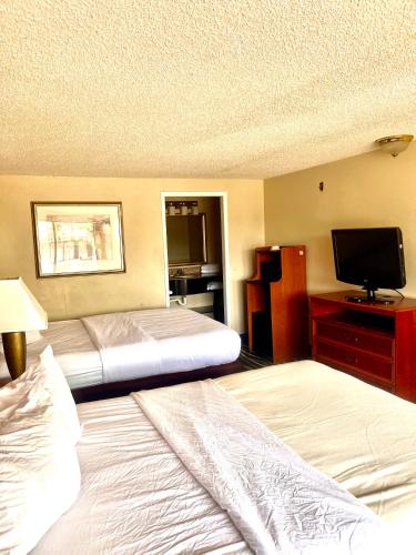 a hotel room with two beds and a flat screen tv at Stay-Well Inn - Monroe in Monroe