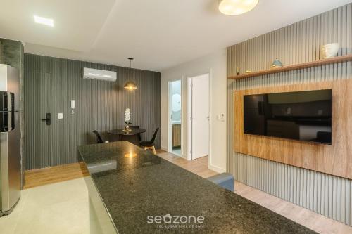 a kitchen and living room with a television and a table at Prédio c/ Aptos Novos a 300m da Praia - EEP in Guarapari