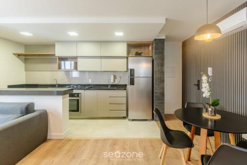 a kitchen and living room with a table and a couch at Prédio c/ Aptos Novos a 300m da Praia - EEP in Guarapari