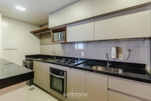a kitchen with white cabinets and a sink at Prédio c/ Aptos Novos a 300m da Praia - EEP in Guarapari