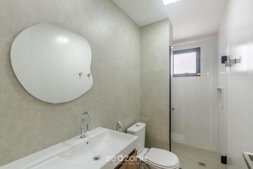 a bathroom with a sink and a toilet and a mirror at Prédio c/ Aptos Novos a 300m da Praia - EEP in Guarapari