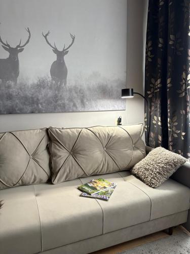 a couch with a picture of deer on the wall at Przytulny Apartament in Ostrowiec Świętokrzyski