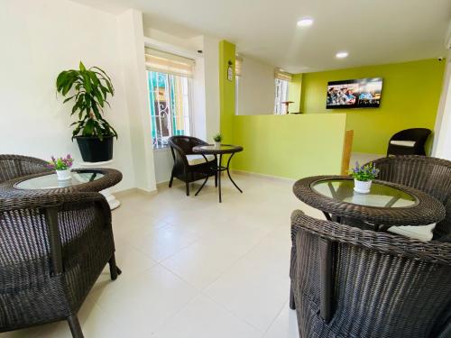 a living room with two tables and chairs and green walls at Hotel Marovi in Santa Marta