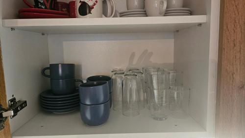 a row of glass jars and plates on a shelf at Emari - Hochwertige 2-Zimmer-Wohnung mit Panorama Bergblick in SJJ