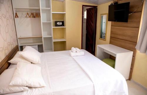 a bedroom with a large white bed and a desk at Pousada Além dos Mares in Fernando de Noronha