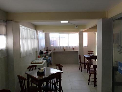 a dining room with tables and chairs and a kitchen at Pousada Além dos Mares in Fernando de Noronha