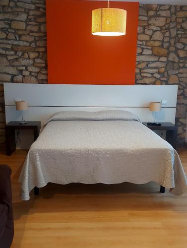 a bedroom with a white bed with an orange wall at Posada Giraldilla in Liérganes