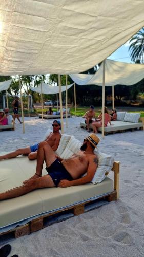 a group of men laying on lounge chairs on a beach at Pink Lemon House in Elche
