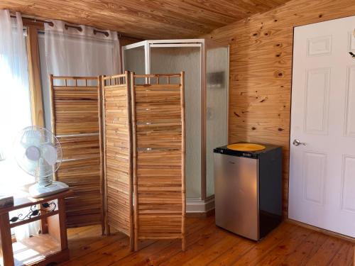 a room with a refrigerator and a wooden wall at La Forillonne in Gaspé