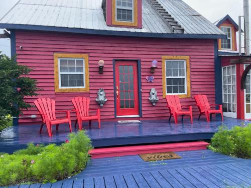 a red house with red chairs on a deck at La Forillonne in Gaspé