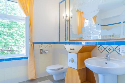 a bathroom with a sink and a toilet and a window at Aparthotel Tři lilie in Františkovy Lázně