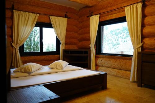 a bedroom with a bed and two windows in it at Mi Chalet - Poiana Izvoarelor in Vatra Dornei