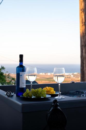 a table with two glasses and a bottle of wine at AetherOia Suites in Oia